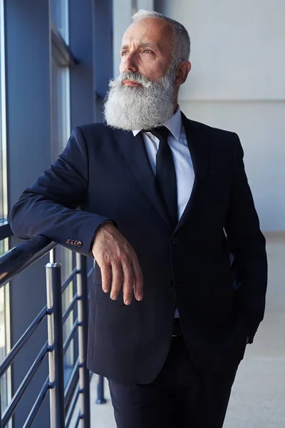 Homem atencioso com barba cinzenta olhando pela janela — Fotografia de Stock