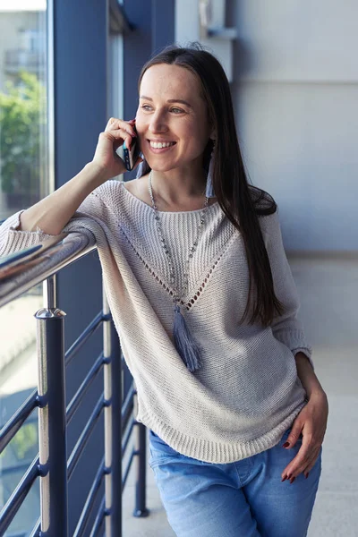 Stijlvolle brunet praten over telefoon terwijl u uitkijkt op venster — Stockfoto