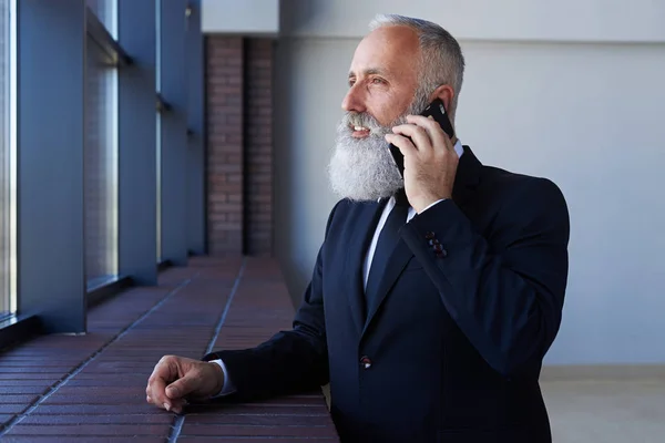 Homem cinzento sólido falando ao telefone enquanto se inclina na soleira — Fotografia de Stock
