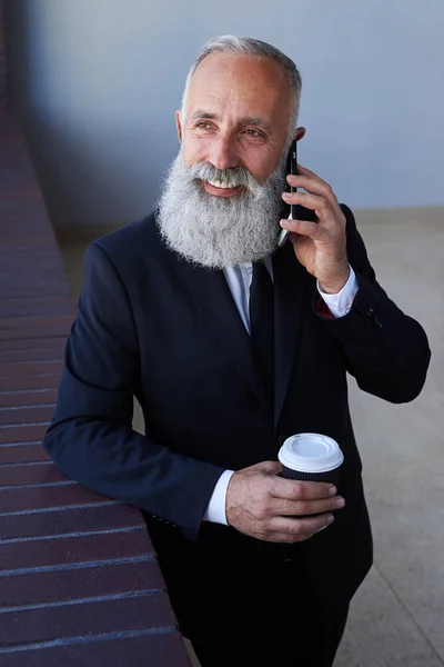 Allegro gentiluomo che parla al telefono mentre tiene in mano una tazza di caffè — Foto Stock