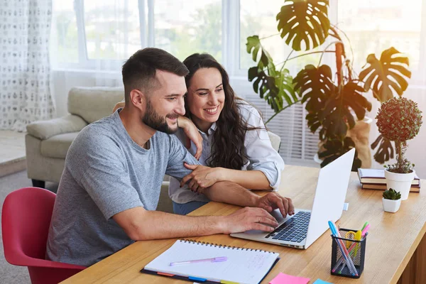 Smiling couple surfing in laptop sitting at table — Stock Photo, Image