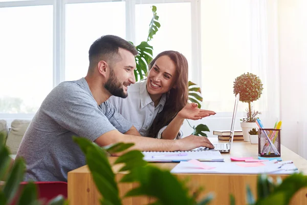 Pleasant girlfriend showing something in laptop to boyfriend — Stock Photo, Image