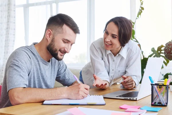 Beautiful female telling something while male writing in noteboo — Stock Photo, Image