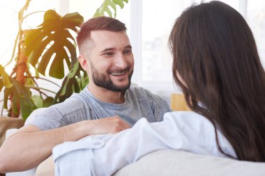 Brunet ve sakallı bir adam kanepede dinlenme yaparken sohbet