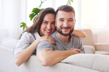 Neşeli brunet ve sarılma ve kanepede rahatlatıcı karanlık adam