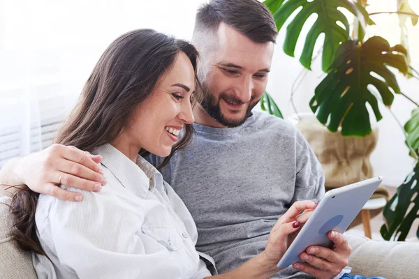 Good-looking male and female sitting on sofa and surfing in tabl — Stock Photo, Image