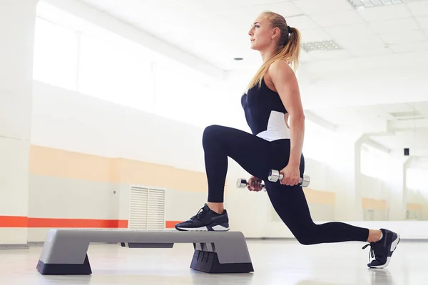 Mujer atlética haciendo ejercicio con pesas en aeróbic paso — Foto de Stock