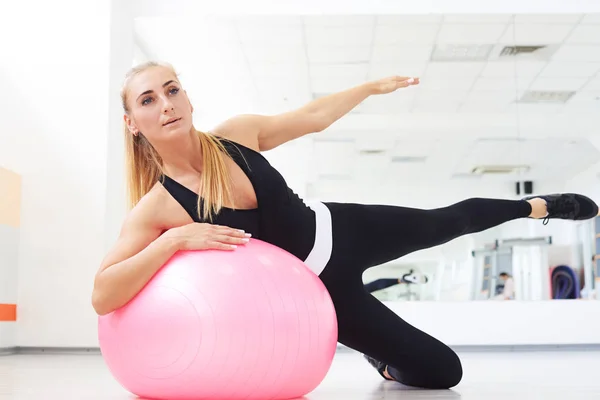 Kadın kapalı spor salonunda yan bend egzersiz egzersiz yaparken fitball üzerinde — Stok fotoğraf