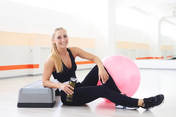 Donna felice e sorridente che beve acqua dopo l'allenamento aerobico — Foto Stock