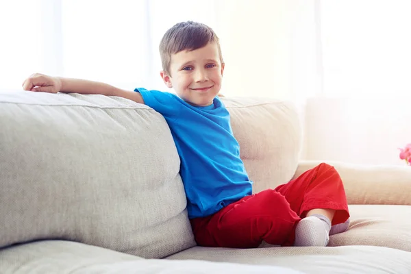 Candid portrait of sweet happy little boy sitting on sofa — Stock Photo, Image