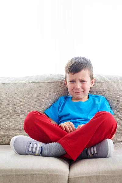 Sorglig liten pojke gråter på soffan — Stockfoto