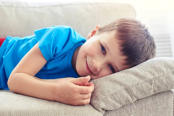 Крупный план красивого мальчика с голубыми глазами, лежащего на подушке — стоковое фото