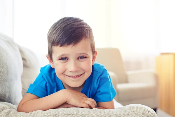 Close-up of boy with cornflower blue eyes lying on sofa — Stock Photo, Image