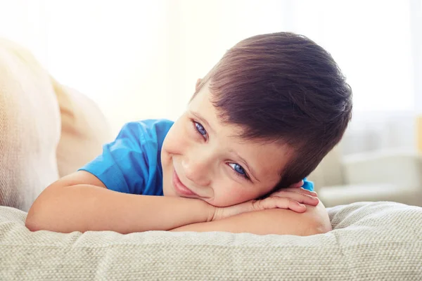 Cute small boy with cornflower blue eyes lying on sofa — Stock Photo, Image