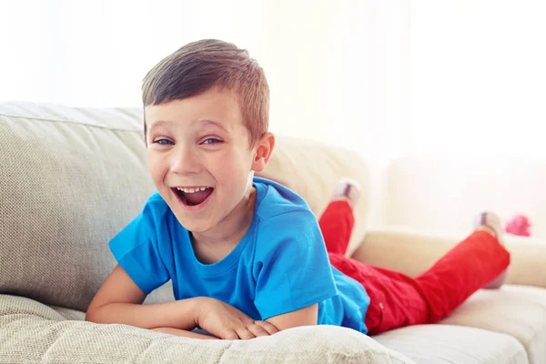 Удивленный маленький мальчик лежит на диване — стоковое фото