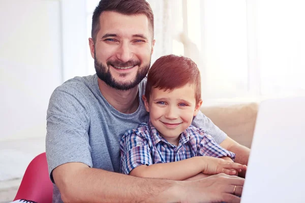 Primer plano del niño pequeño sentado con el padre en la mesa y usando — Foto de Stock