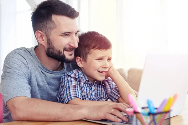 Padre e hijo usando portátil en la mesa en casa — Foto de Stock