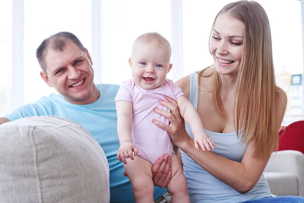 Beautiful mother holding baby while sitting with dad on sofa — Stock Photo, Image