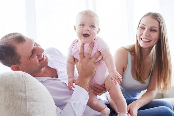 Hombre guapo sosteniendo sonriente niño mientras está sentado con su esposa en — Foto de Stock