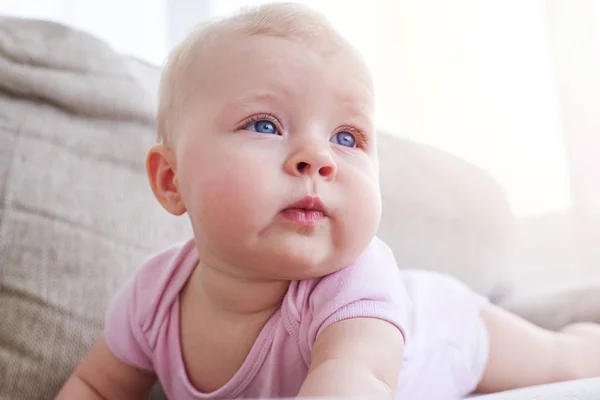 Sweet baby lying on sofa and looking somewhere — Stock Photo, Image