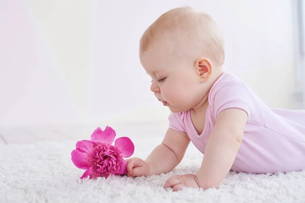 Niedliches Baby, das eine Blume betrachtet — Stockfoto