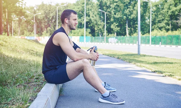 Atleta serio seduto sul marciapiede — Foto Stock