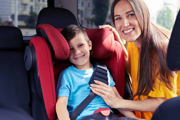 Smiling mother checking seat belt of son sitting in baby seat — Stock Photo, Image