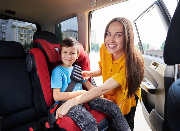 Wdzięku Mama sprawdzanie syn siedzi w fotelik dla dziecka — Zdjęcie stockowe