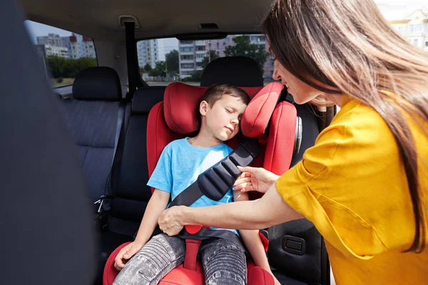 Caring mother checking seat belt sleeping son — Stock Photo, Image