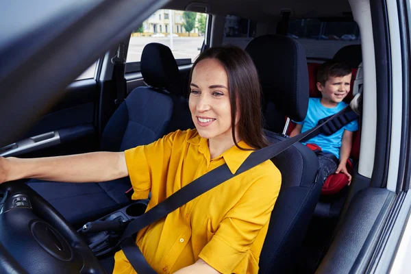 Mulher dirigindo um carro, criança atrás — Fotografia de Stock