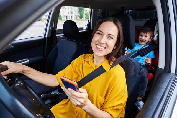 Usmívající se matka řídit auto, telefon — Stock fotografie