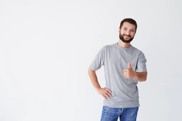 Brunet segurando o polegar contra fundo branco — Fotografia de Stock