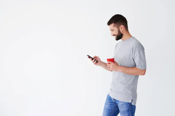 Moderne casual mens met behulp van telefoon en koffie drinken uit papier gla — Stockfoto