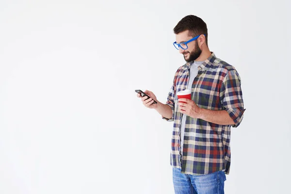 Jonge man in casual kleding, drinken koffie en het gebruik van de telefoon — Stockfoto