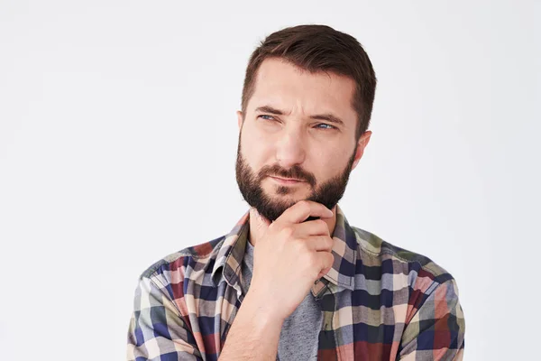 Handsome thoughtful man with beard holding hand on chin looking — Stock Photo, Image