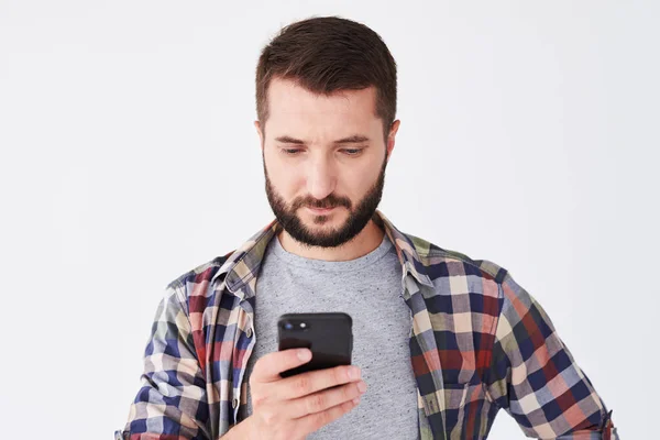 Joven barbudo con camisa a cuadros usando smartphone —  Fotos de Stock