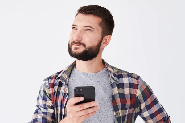 Hombre barbudo pensativo mirando hacia arriba mientras envía mensajes de texto por teléfono — Foto de Stock