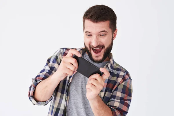 Emocionado hombre barbudo con camisa a cuadros jugando en el teléfono inteligente — Foto de Stock