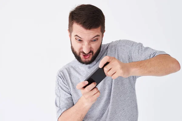Emotionele jonge bebaarde man spelen op smatphone — Stockfoto