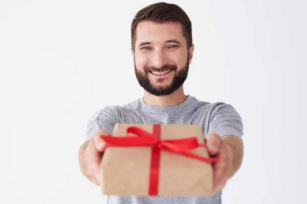 Knappe bebaarde man in vrolijke stemming houden cadeau en glimlachen — Stockfoto