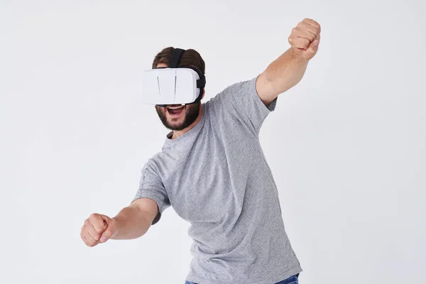 Energetic bearded man in VR glasses stretching his hands out as — Stock Photo, Image