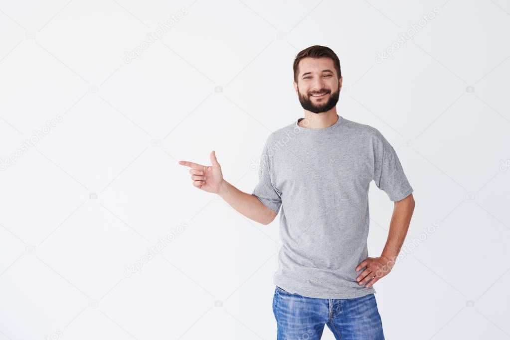 Smiling bearded man pointing to the copy space indoors