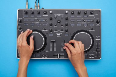 DJ mixer mavi arka plan üzerinde oynarken eller