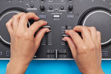Dj mikser ile mavi arka plan üzerinde çalışan kız eller