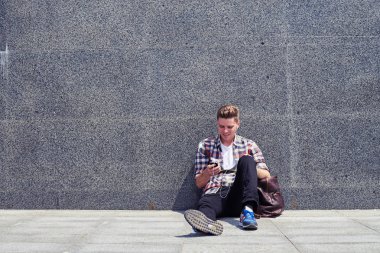 Kaygısız öğrenci müzik dinlerken duvara yaslanmış 