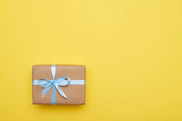 Плоская раскладка подарков, украшенная синей лентой на желтом фоне — стоковое фото