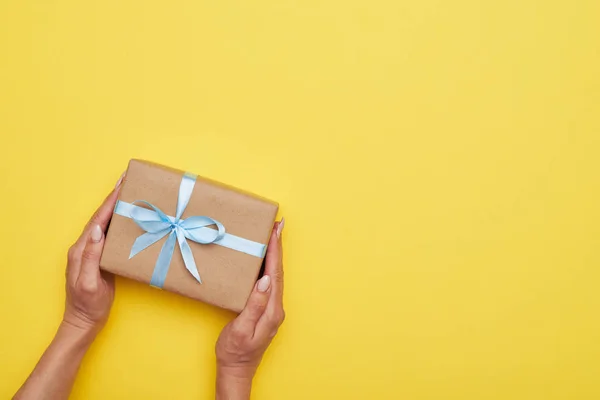 Fantástico regalo envuelto decorado con arco en manos de mujer — Foto de Stock