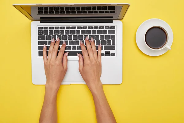 Рабочее место с женскими руками печати в ноутбуке и чашку кофе — стоковое фото