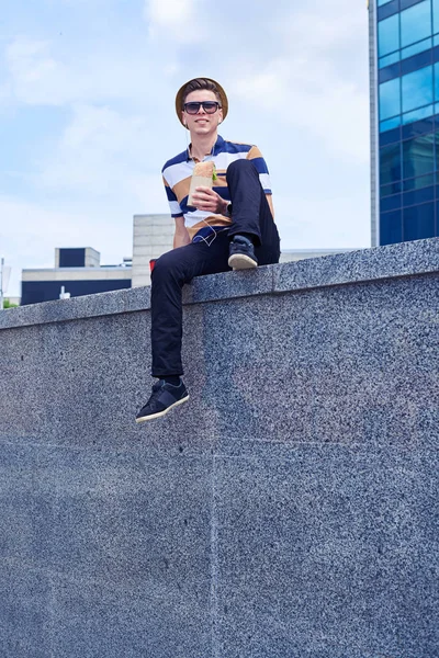 Bel ragazzo che si gode il panorama della città mentre pranza fuori casa — Foto Stock