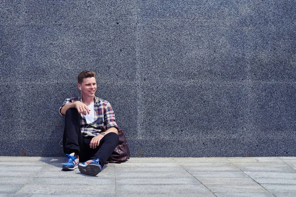 Un bell'uomo appoggiato al muro mentre ascolta la musica — Foto Stock